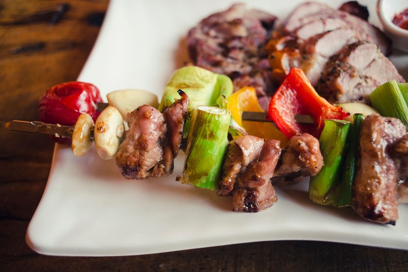 Grilled meat kabob with peppers, onion and mushrooms on a white plate