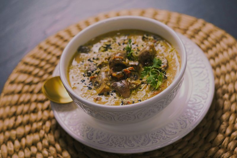 Creamy chicken soup in a white bowl on a woven placemat