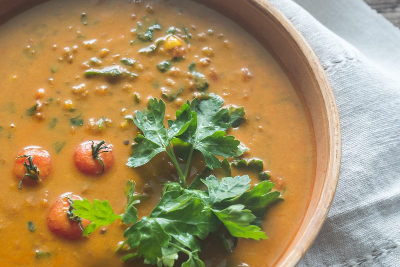 Bowl of lentil curry topped with fresh parsley and cherry tomatoes