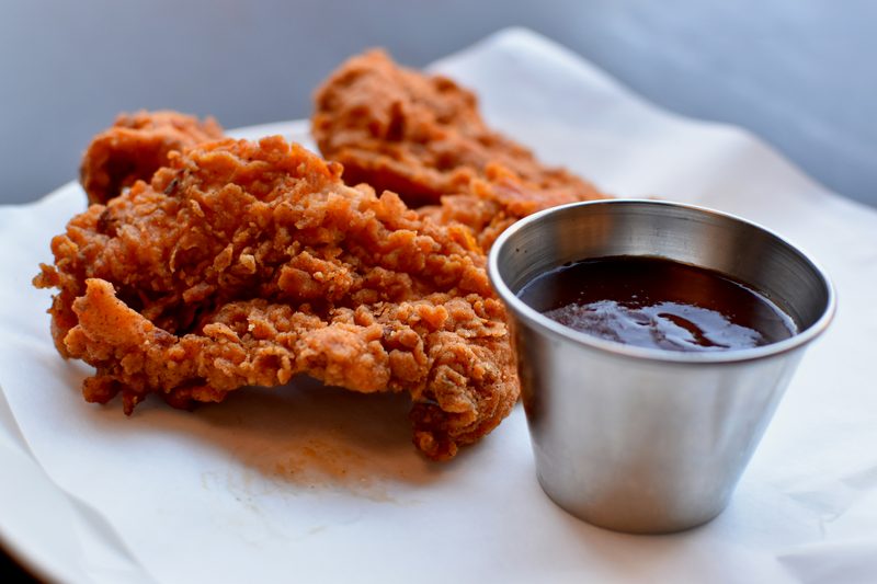 Crispy breaded, fried strips on parchment with a cup of dipping sauce