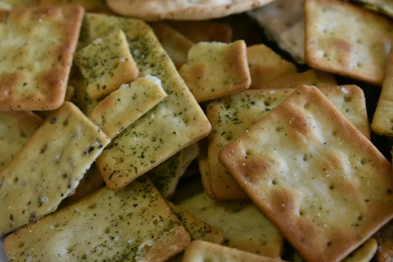 Pile of crisp crackers flecked with dried herbs