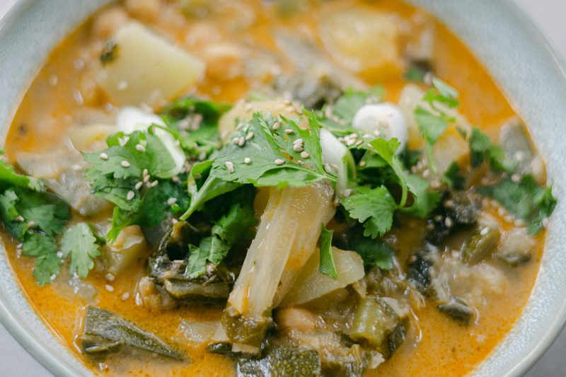 Creamy soup with potatoes and leafy greens in a white bowl
