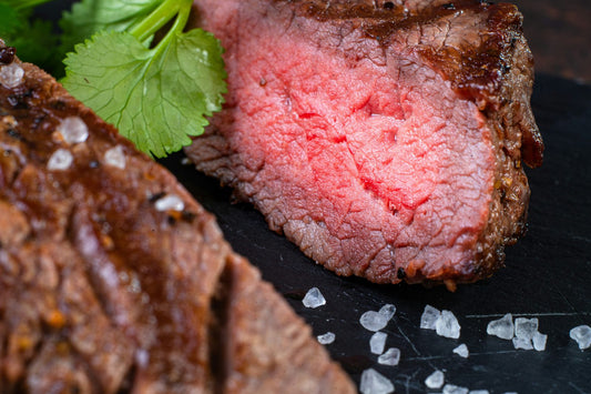 Sliced roast beef with a dark peppery crust and a rosy pink center, with coarse salt