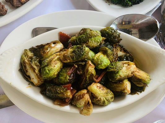 Roasted Brussels sprouts with browned, crispy edges in a white serving dish