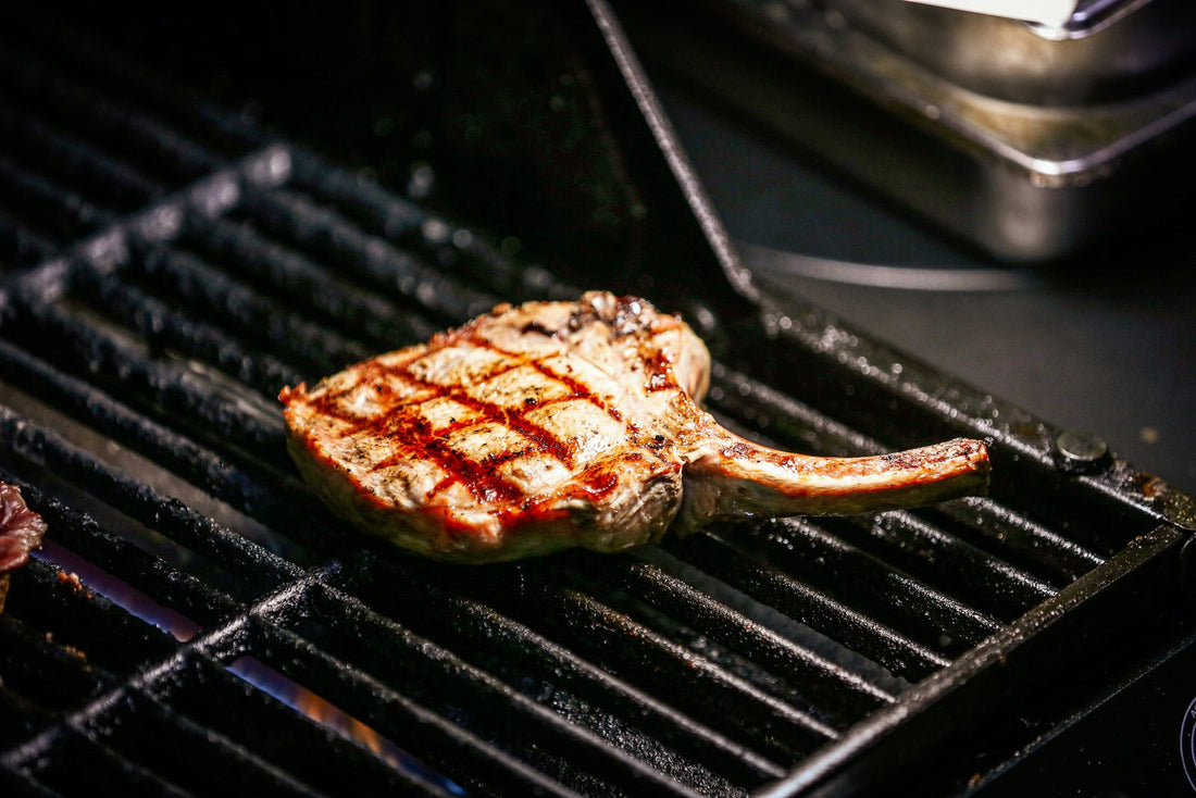 Bone-in pork chop with grill marks on a hot grill grate