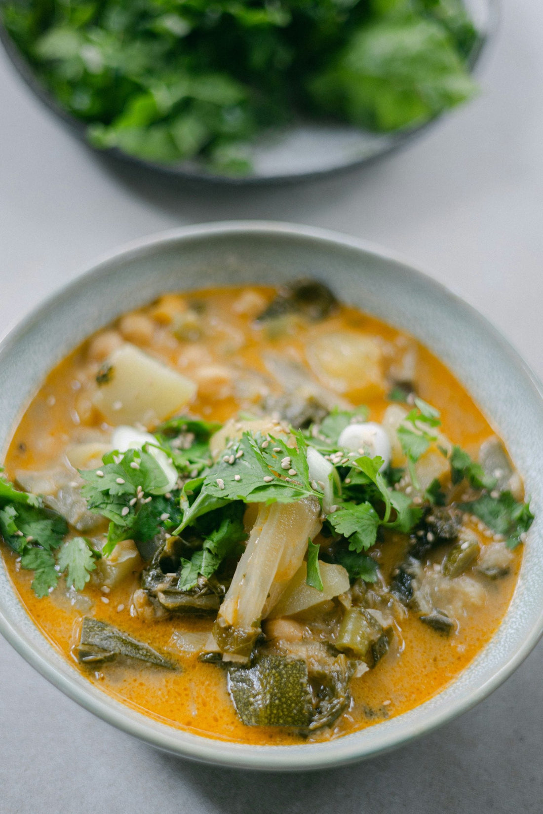 Creamy soup with potatoes and leafy greens in a white bowl