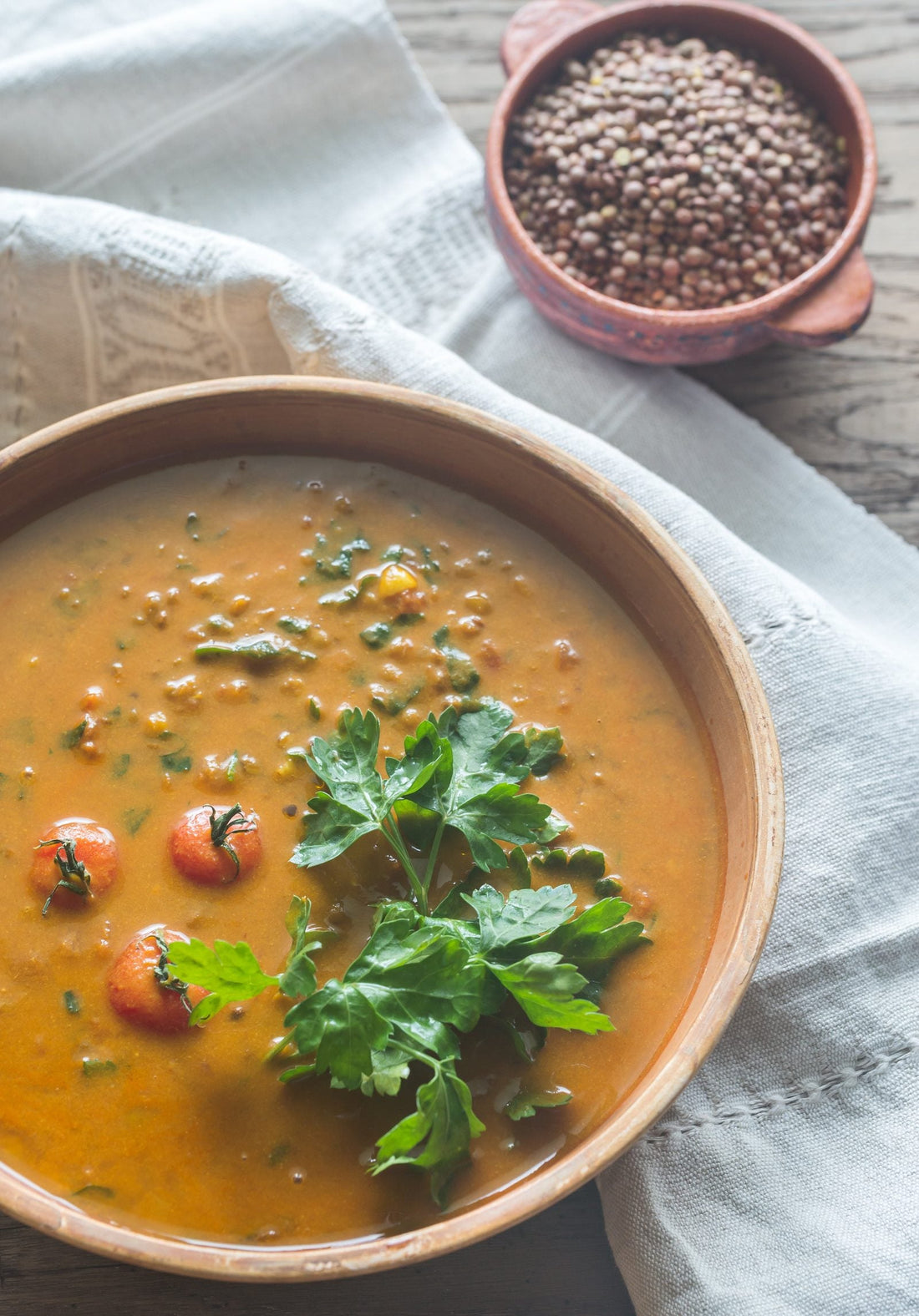 Bowl of lentil curry topped with fresh parsley and cherry tomatoes