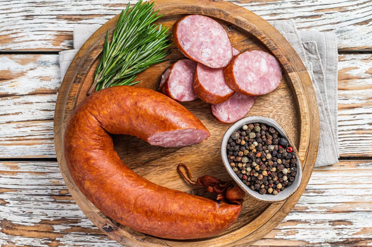 Joe Bant sausage on a wooden board with herbs. White wood