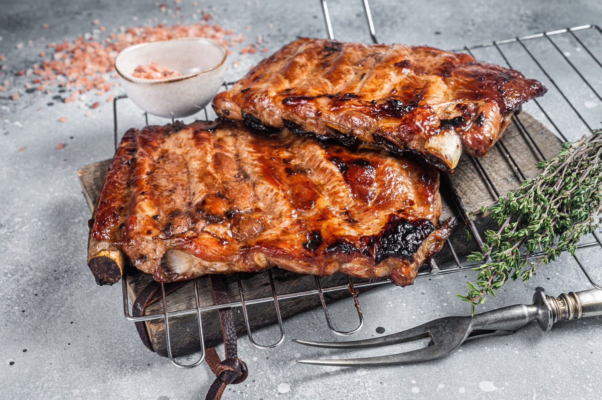 BBQ grilled pork ribs in Barbecue sauce on a grill. Gray backgro