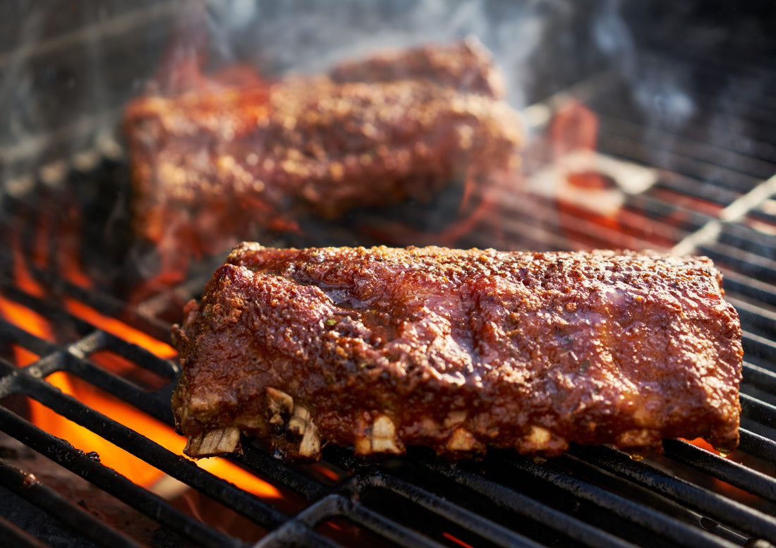 Pork ribs grilling over open flames