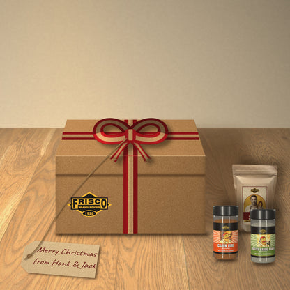 Hank & Jack Deer Camp Gift Box: tied with a red and kraft ribbon on a wood table, with a 'Merry Christmas from Hank & Jack' tag