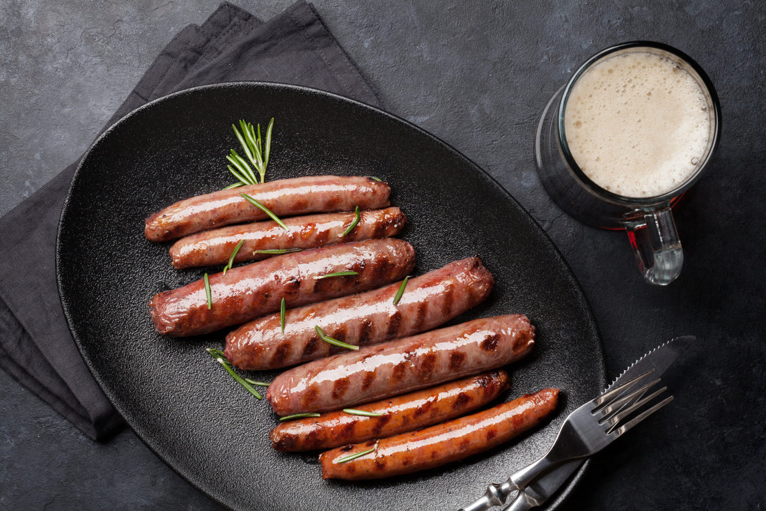 Grilled bratwurst with a glass of beer on a dark table