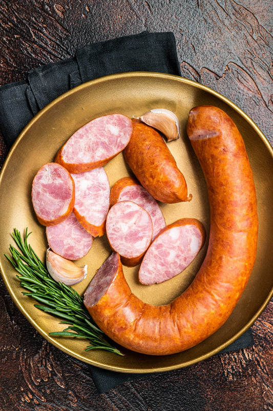 Polish Smoked sausage in a steel plate. Dark background. Top vie