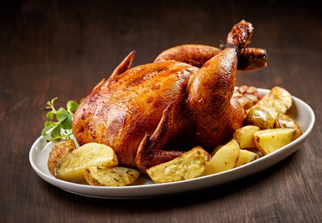 Whole roast chicken with potatoes on dark wood
