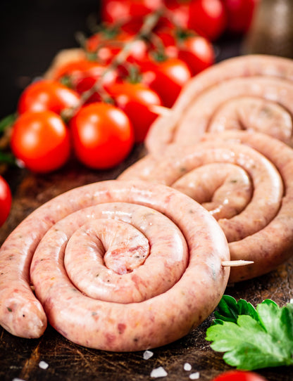 Round raw sausages with tomatoes and parsley.