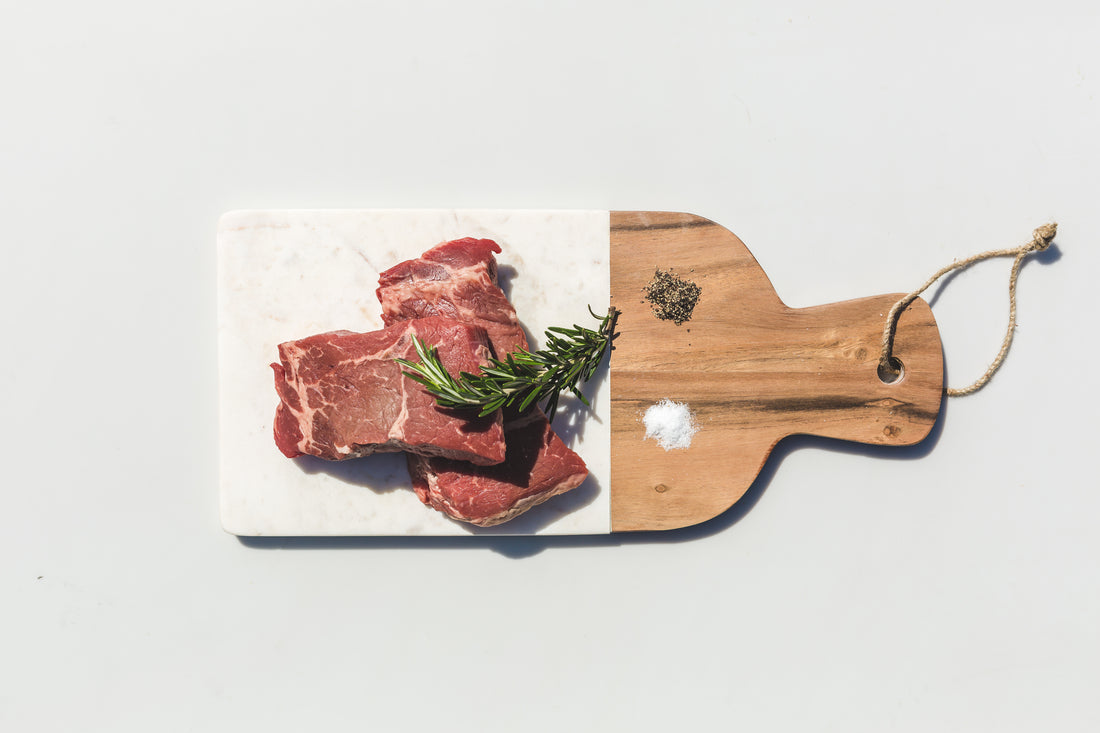 Raw steaks with rosemary on a board, ready to season