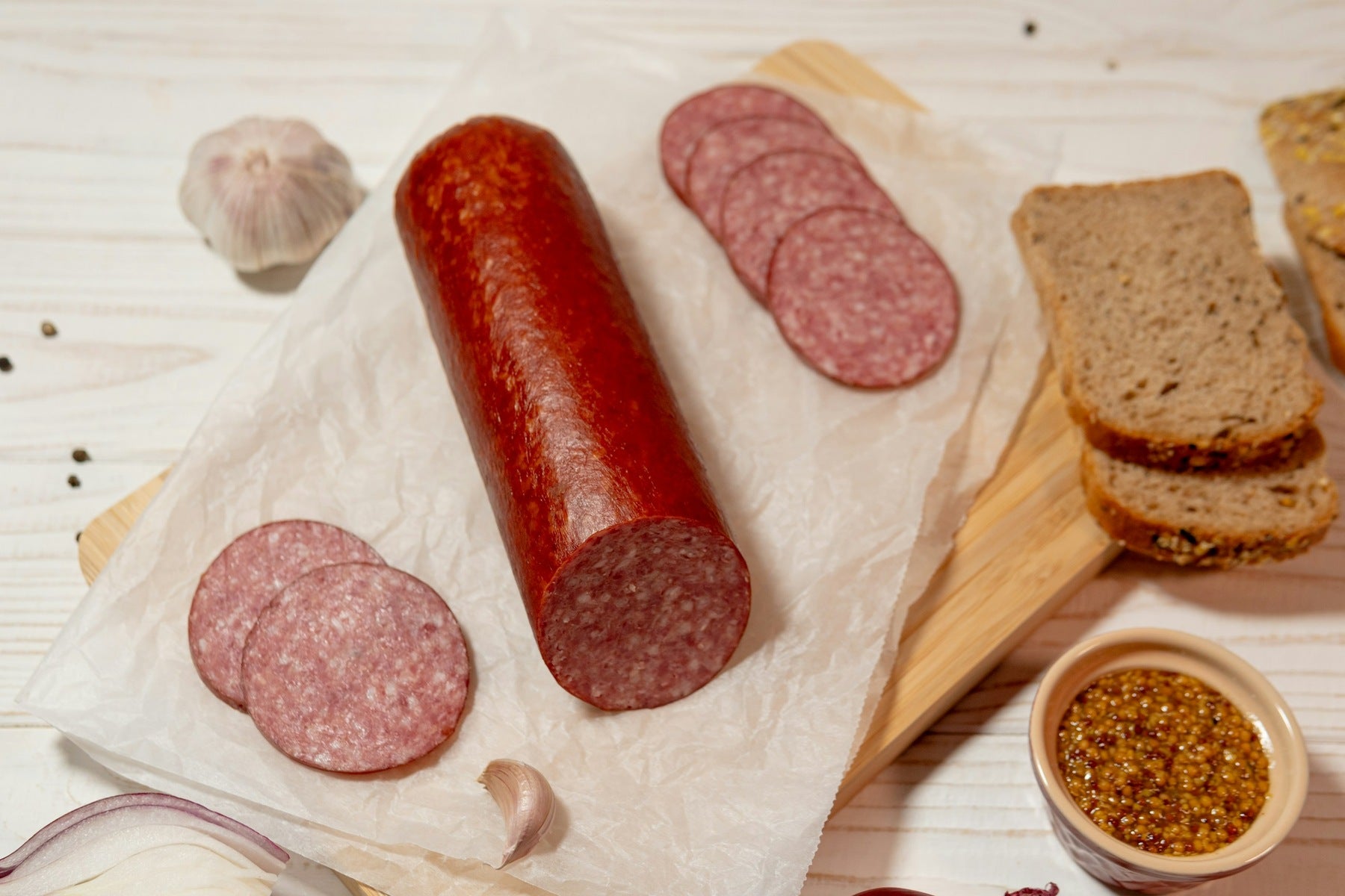 Whole summer-style sausage with slices, rye bread and mustard
