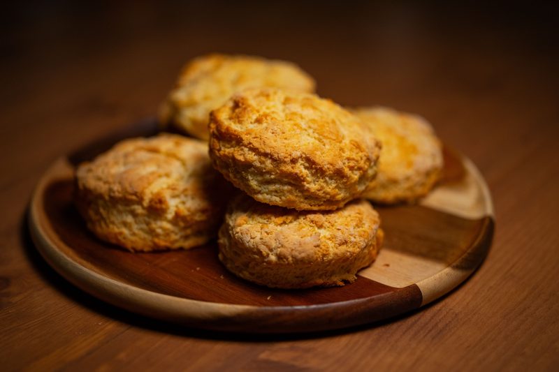 Stack of golden, flaky biscuits on a wooden plate