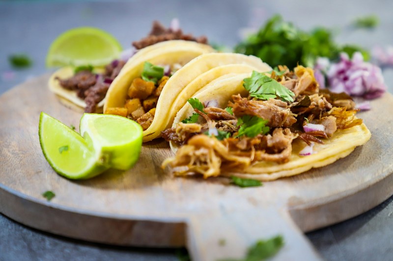 Three soft tacos with cilantro, onion and lime