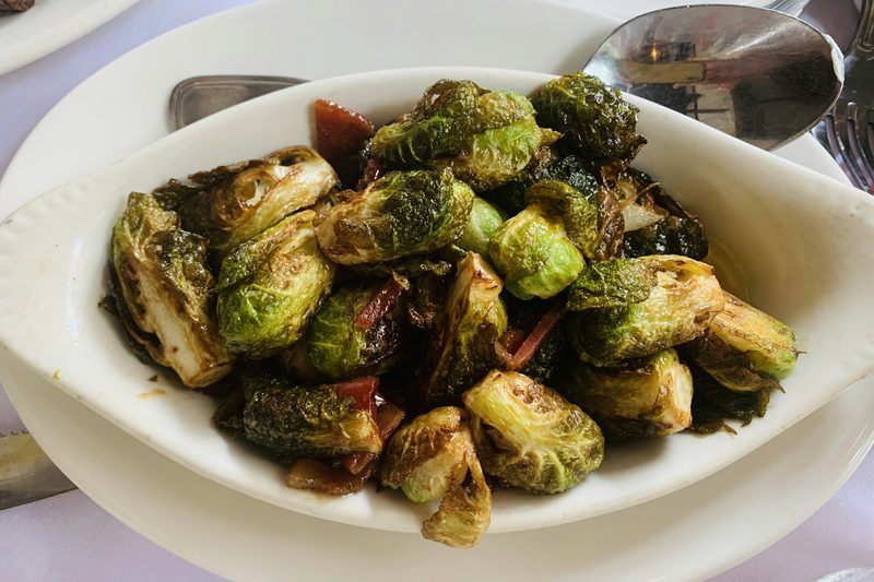 Roasted Brussels sprouts with browned, crispy edges in a white serving dish